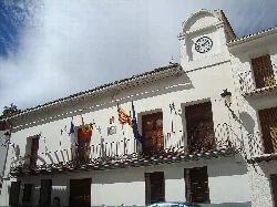 Edificio blanco con reloj y banderas en el balcón.