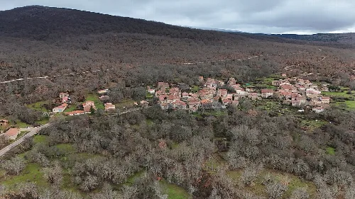 Aerial view of a monastery in a mountainous area with houses and trees.
