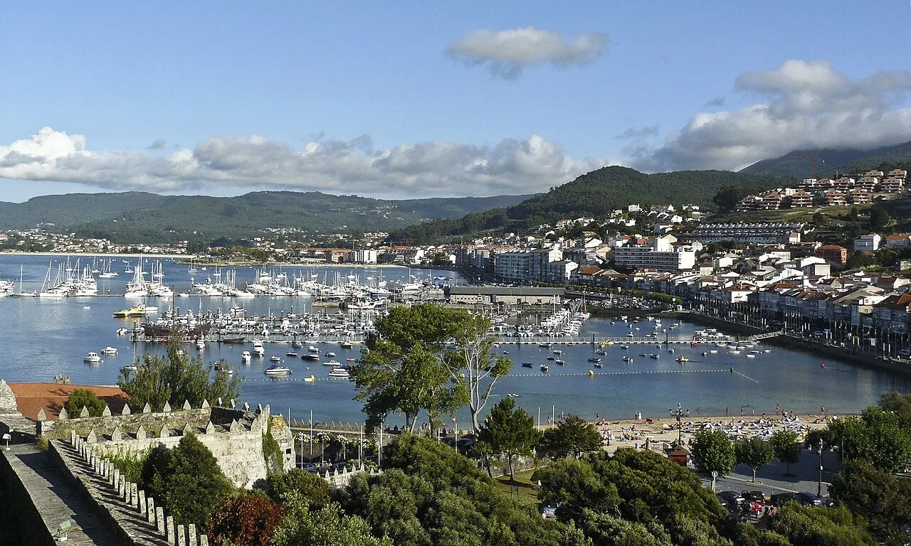 View of Baiona's port with boats and hills in the background.
