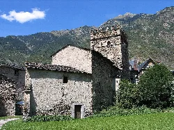 Torre antigua de piedra en Benasque con montañas al fondo.
