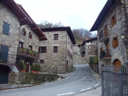 Calles empinadas con casas de piedra y balcones de madera en Arano, Navarra.