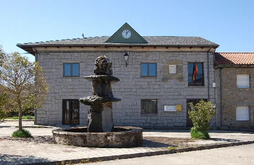 Steinernes Gebäude mit Uhr und Brunnen auf dem Hauptplatz von Cernadilla.