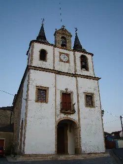 Fachada de la iglesia con dos torres y reloj en Puerto de Vega.