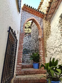 Brick and tile archway in Alfarnate with potted plants