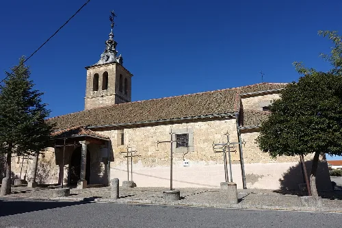 Church of San Juan Evangelista in Marazoleja, Segovia, with tower and stone facade.