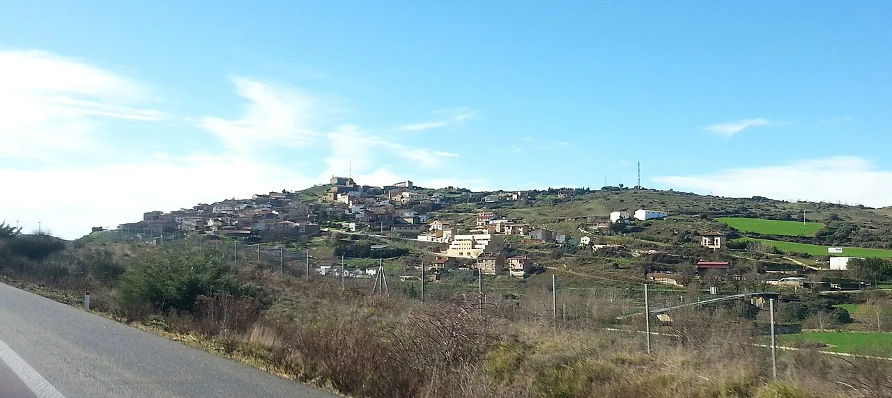 Blick auf Pueyo, Navarra, mit Häusern auf einem Hügel und blauem Himmel.