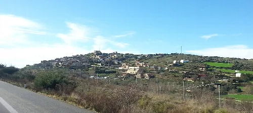 Vista de Pueyo, Navarra, con casas en una colina y cielo azul.
