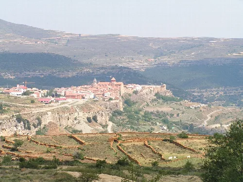 Blick auf eine Stadt auf einem Hügel mit landwirtschaftlichen Feldern im Vordergrund.