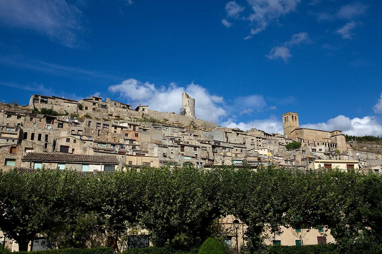 Häuser auf einem Hügel mit blauem Himmel und Wolken.