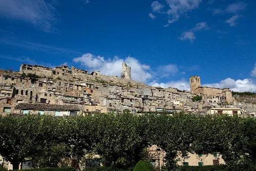 Häuser auf einem Hügel mit blauem Himmel und Wolken.