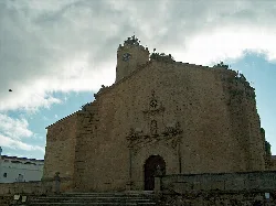 Steinfassade der Kirche mit Glockenturm in Malpartida de Cáceres.