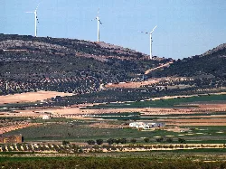 Paisaje rural con colinas, campos agrícolas y aerogeneradores en la Sierra del Romeral.