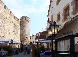 Straße mit Restaurants und einem mittelalterlichen Turm in Tossa de Mar.