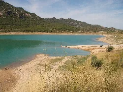 Calanda Stausee mit blauem Wasser und Bergen im Hintergrund.