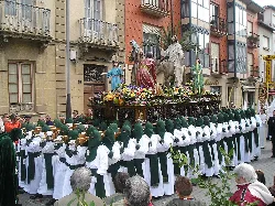 Procesión con figuras religiosas y participantes en trajes de colores en Astorga.