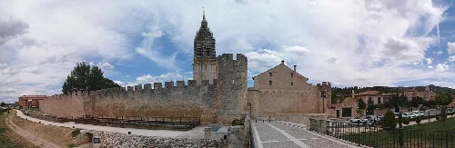 Stadtmauer und Turm der Kathedrale in El Burgo de Osma bei bewölktem Himmel.