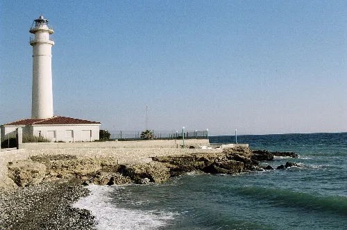 Leuchtturm und Küste von Torrox mit klarem Himmel und ruhigem Meer.
