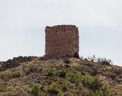 Torre de las Encantadas in Sabiñán, Zaragoza, auf einem Hügel mit Vegetation.