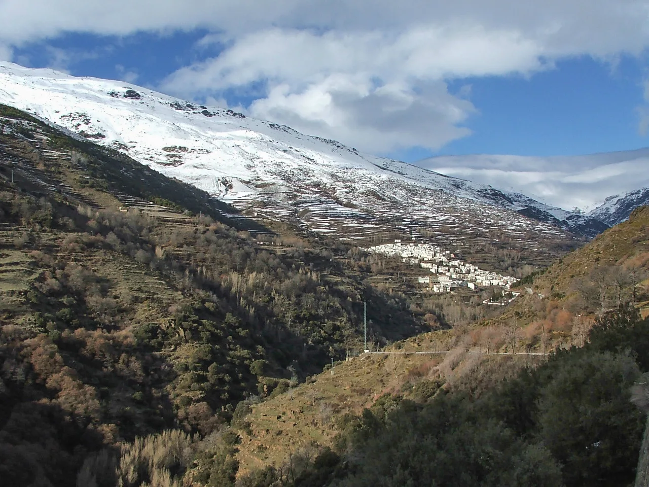 Paisaje de montaña con casas blancas en Trevélez y nieve en las cumbres.