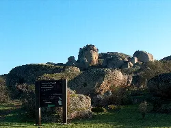 Große Felsformationen und ein Infotafel in einem Naturpark.