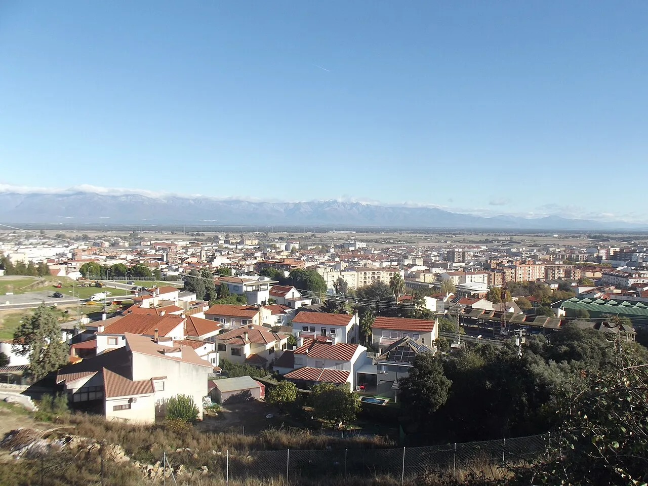 City view with houses and snow-capped mountains in the distance.