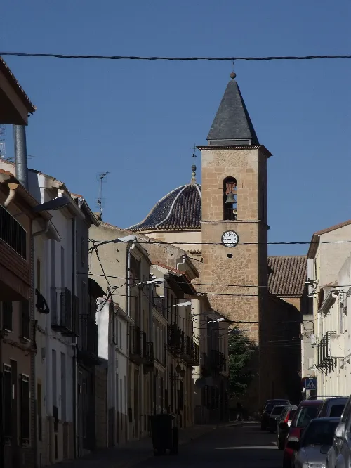 Campanario de una iglesia con casas a su alrededor en Alpera.