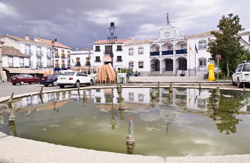 Square with pond, white buildings, and town hall in Hinojosa del Duque.