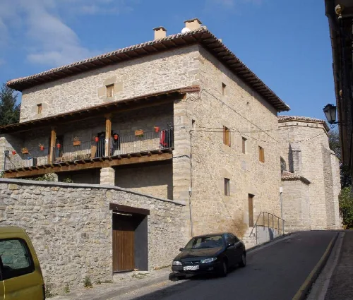 Casa de piedra con balcón de madera y tejado de tejas en Zizur Mayor.