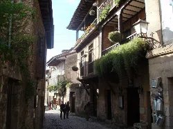 Street in Santillana del Mar with stone houses and balconies with plants.