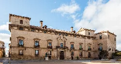 Stone palace facade with multiple windows and a central door in Almazán.