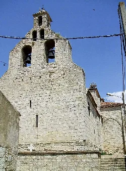 Torre de piedra con campanas y cielo azul en Monzón de Campos.