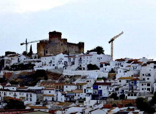 Castillo en lo alto de una colina con casas blancas alrededor.
