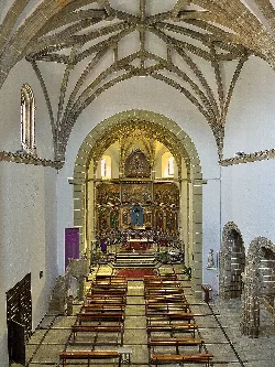 View of the interior of a church with vaults and a decorated altar.