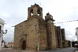 Fachada de piedra de la iglesia con campanario en La Roca de la Sierra.