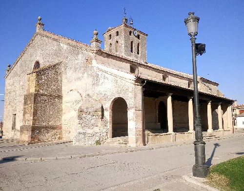 Church of St John the Baptist with stone facade and porch in Aldea Real.