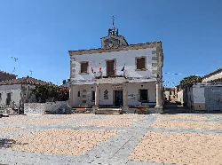 Town hall building with white facade and clock on top.