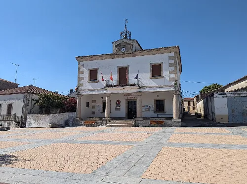 Town hall building with white facade and clock on top.