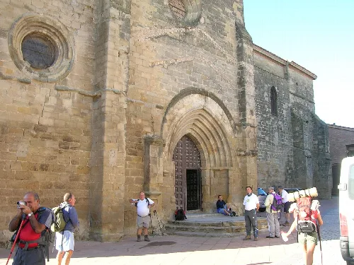 Fassade einer alten Steinkirche mit Touristen am Eingang.
