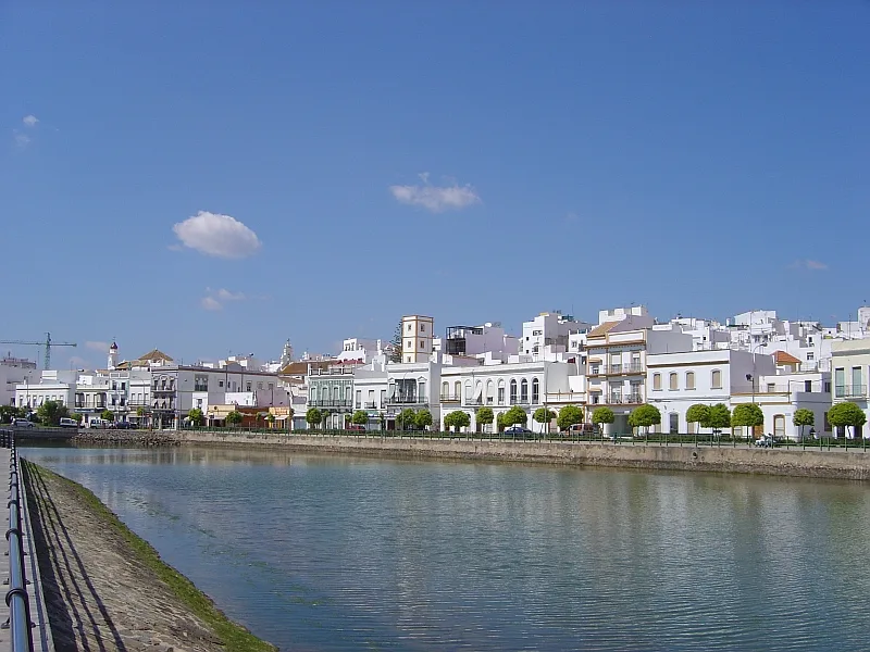Casas blancas junto a un río en Ayamonte, Andalucía, con cielo azul.