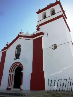 Weiße Kirche mit Glockenturm und Kreuz in Cheles, Badajoz.