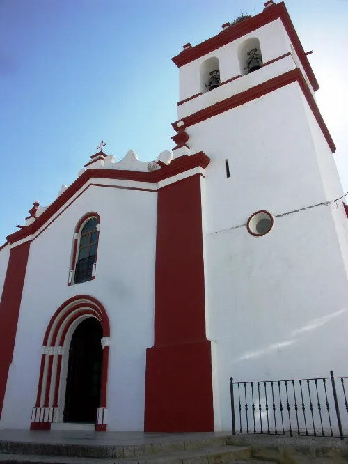 Weiße Kirche mit Glockenturm und Kreuz in Cheles, Badajoz.