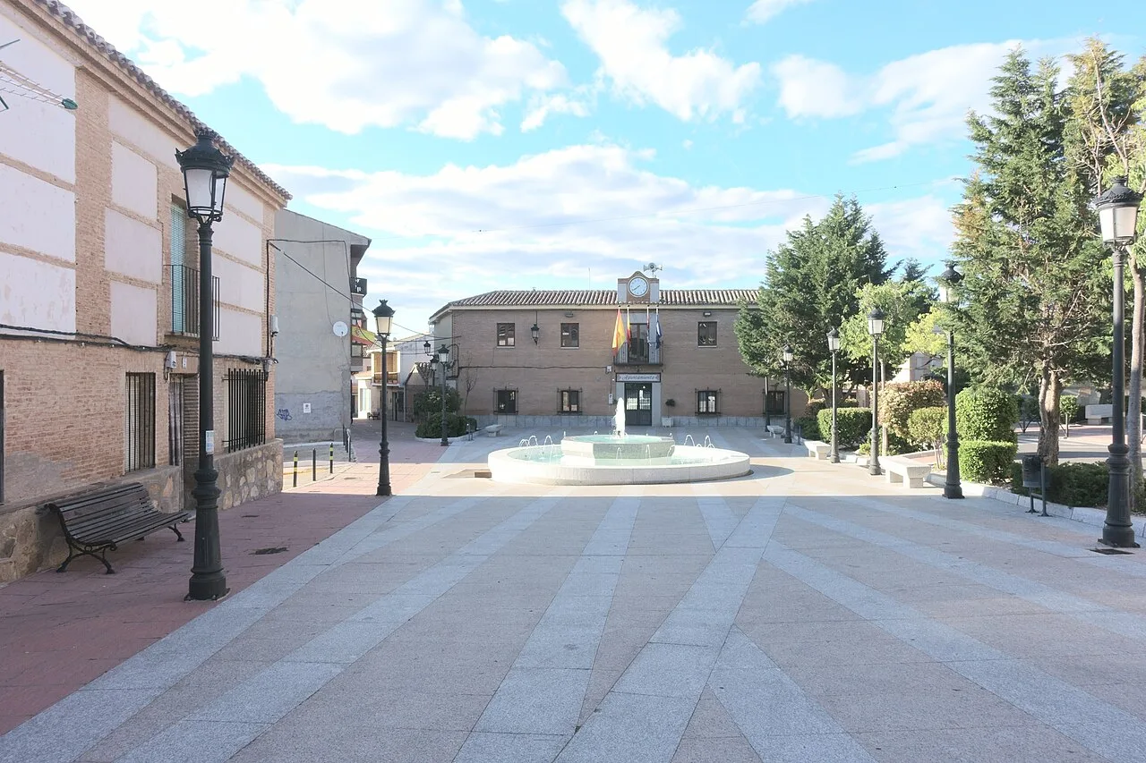 Plaza con fuente, bancos, árboles y farolas en Cobisa.