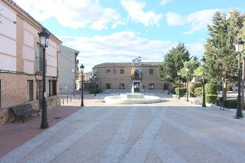 Plaza con fuente, bancos, árboles y farolas en Cobisa.