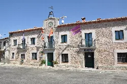 Stone building with clock and flags on the town hall facade.