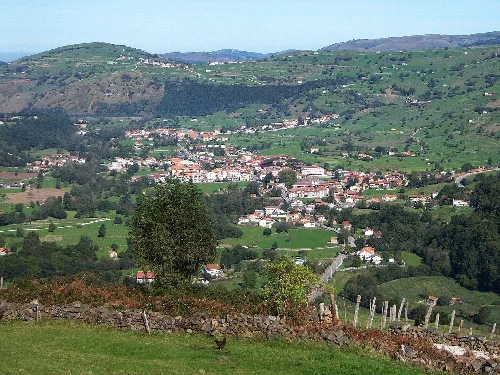 Paisaje de colinas verdes con casas y árboles en Selaya, Cantabria.