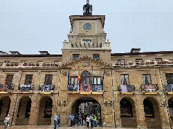 Edificio del ayuntamiento con reloj y banderas en Oviedo.