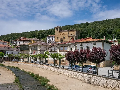 Houses and a church in Marañón, Navarre, with trees and cars on the street.