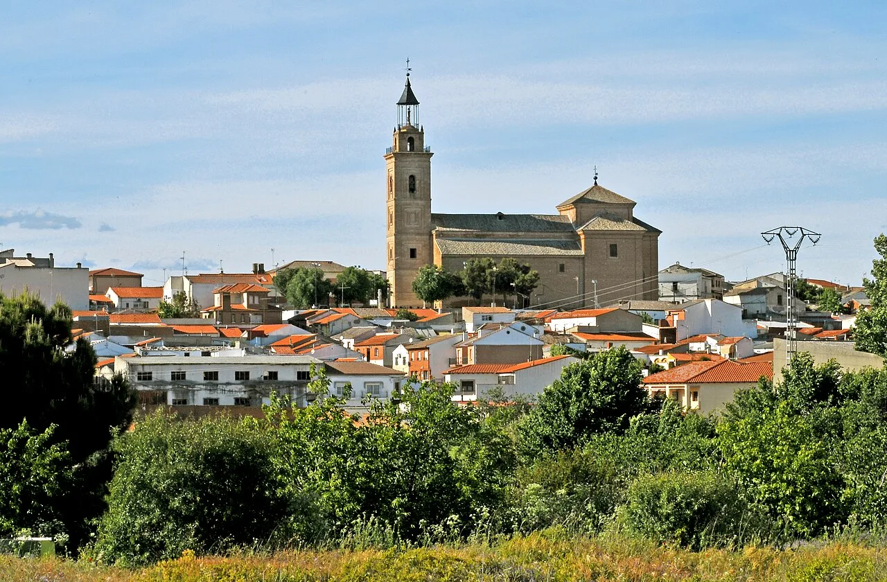 Ansicht der Pfarrkirche und Gebäude in Cebolla, Toledo, unter blauem Himmel.