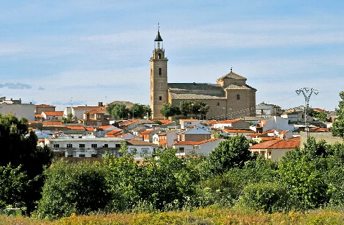 View of the parish church and buildings in Cebolla, Toledo, under a blue sky.