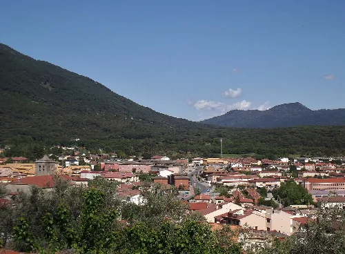 Blick auf eine Stadt mit Bergen und Hügeln im Hintergrund.
